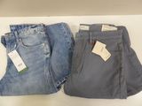 two pairs of jeans are sitting on a table with a price tag