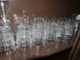 bottles and glasses are lined up on a shelf in a room