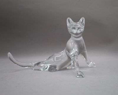 a glass figurine of a cat sitting on the ground
