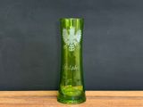 a green glass vase sitting on a wooden table