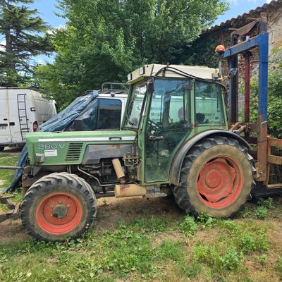 un vieux tracteur vert garé dans un champ à côté d'une maison