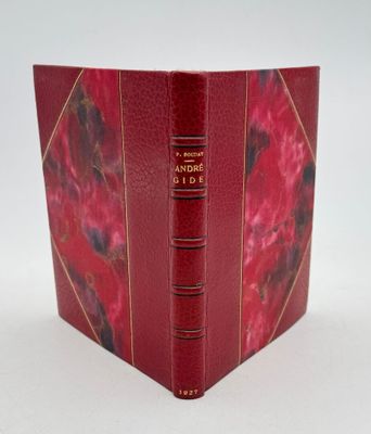 un vieux livre à la couverture rouge posé sur une table blanche