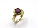 gros plan d'une bague en or avec une pierre violette