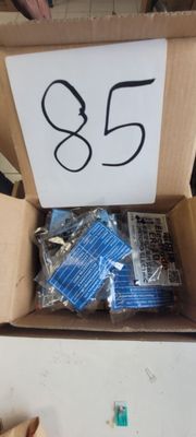une boîte en carton remplie d'objets divers et une pancarte sur laquelle est inscrit « 85 »