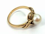 an image of a pearl and gold ring on a white surface