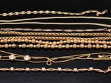 several gold chains and bracelets on a black surface