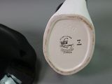 a white and black vase sitting next to a black and white cup
