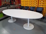 a white oval table in a room with chairs