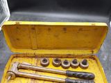 une mallette à outils jaune, contenant des outils, posée par terre