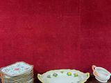 de nombreuses assiettes et tasses posées sur une table, avec un mur rouge en arrière-plan