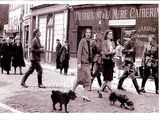 a black and white photo of people walking down the street with a dog