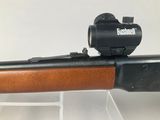 the rifle has a red dot on it ' s sight on the side of the rifle