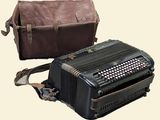 a black accordion sitting next to a brown bag