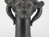 une image représentant une sculpture représentant la tête d'une femme, les mains posées sur la tête