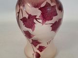 purple and white vase with red leaves on it sitting on a white surface