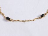 an image of a gold necklace with black stones on a white background