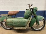an old green moped parked in front of a white wall