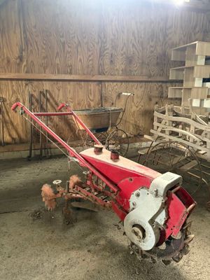 un tracteur rouge équipé d'une charrue, dans une grange