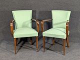 pair of green upholstered chairs against a gray background