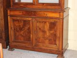 a wooden cabinet with a glass door and a chair in front of it