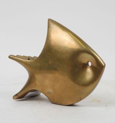brass fish sculpture on a white surface with a white background