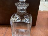 a glass bottle sitting on a table with a wooden box in the background