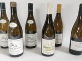 six bottles of wine are lined up in a row on a white surface