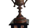 a large ornate bronze vase on a stand on a white background