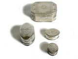 une petite boîte en argent et deux pièces de monnaie posées sur une surface blanche