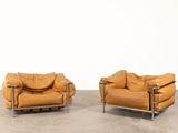 two brown leather chairs sitting next to each other on a cement floor
