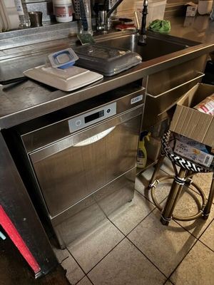une cuisine équipée d'un plan de travail en inox et d'un lave-vaisselle