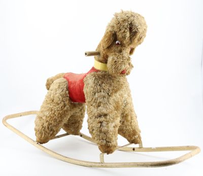 a small toy dog on a rocking horse on a white background