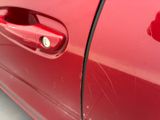 a close up of a red car door handle with a hole in it