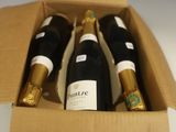 trois bouteilles de vin dans un carton sur une table