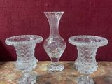 trois vases en verre posés sur une table, avec un mur rouge en arrière-plan