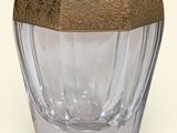 un vase en verre avec un couvercle doré, posé sur une surface blanche