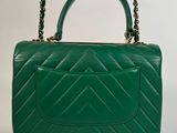 a green handbag with a chain strap and a clasp