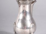 a silver coffee pot sitting on a stand on a white surface