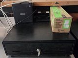 une boîte posée sur une caisse enregistreuse, elle-même posée sur un bureau
