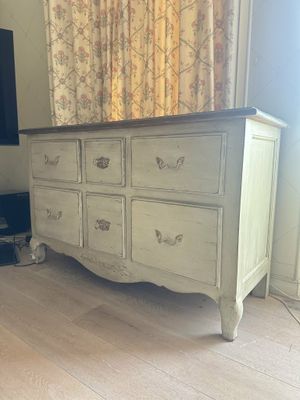a white dresser in a room with a tv on the wall