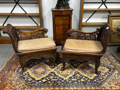 une paire de chaises en bois sculpté avec des coussins rembourrés, posées sur un tapis