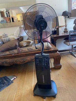 un ventilateur posé sur un pied dans un salon