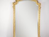 un miroir à cadre doré posé sur une table près d'un mur