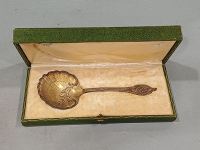 a gold spoon in a green box on a table