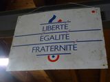 une pancarte sur laquelle on peut lire « liberté, égalité, fraternité » et « fratermite », suspendue au plafond