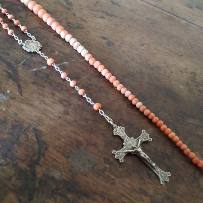 deux grains de chapelet avec une croix posés sur une table en bois