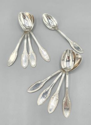 une paire de cuillères en argent et des cuillères posées sur une table