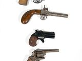 trois vieux revolvers sont alignés sur une surface blanche