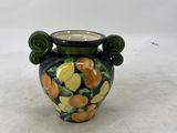 a small vase with a green handle on a white surface