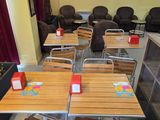 Des tables et des chaises sont alignées dans une pièce aux rideaux rouges